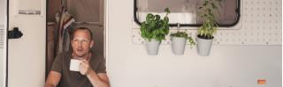 man zittend in deuropening caravan