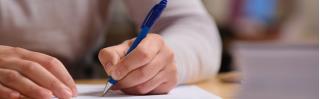 man schrijft met pen iets op papier